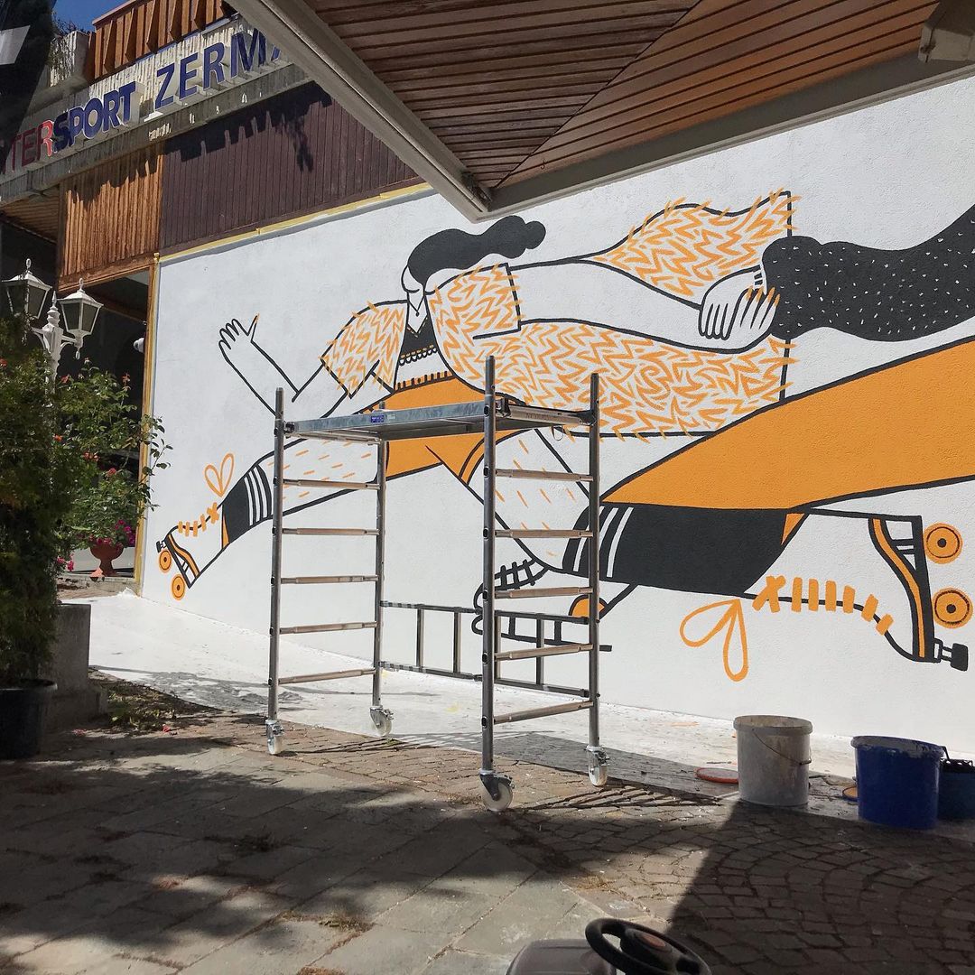 Fresque mural représentant un personnage qui fait du patin à roulette en cours de réalisation avec une échelle au premier plan